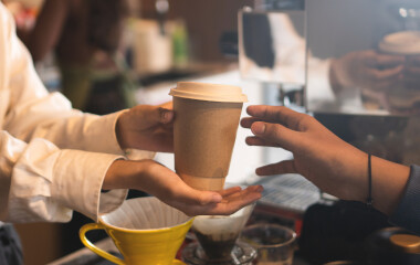  Überreichter Kaffeebecher in einer Bäckerei