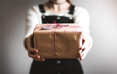 Ein Geschenk das durch eine Person mit ausgestreckten Armen hochgehalten wird