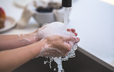 Eine Person die die Hände unter einem Waschbecken wäscht
