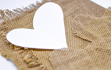 Der Stoff Jute ist Flach auf einer Fläche ausgebreitet und Herzformen aus Papier & Jute liegen darauf