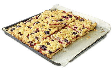 Ein Backplech, dass mit einem Kuchen befüllt ist, der auf einem Backtrennpapier liegt